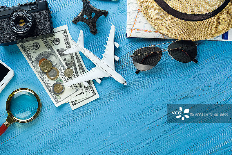 夏季假期物品：相机、太阳镜、现金、草帽、手机、地图和旅行计划。游客布局设置和旅行者配件，在木制背景上。开放边界概念，实现自由快乐的旅行。文本空间的副本。图片素材
