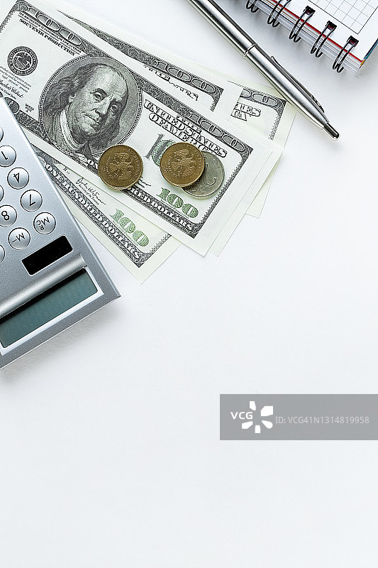 白色桌子上的计算器、笔、打开的笔记本和美元纸币。经济实体的财务会计概念，企业损益计算，费用和收入管理。文本空间副本图片素材