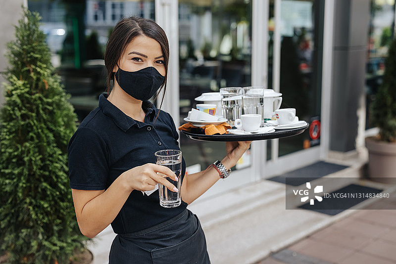 戴口罩的女服务员在露台餐厅为顾客提供服务图片素材
