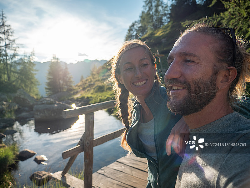 情侣在日出时于湖边码头放松图片素材