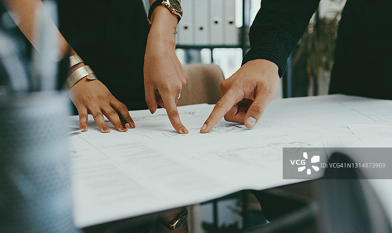 两位身份不明的建筑师在办公室分析蓝图的特写镜头图片素材