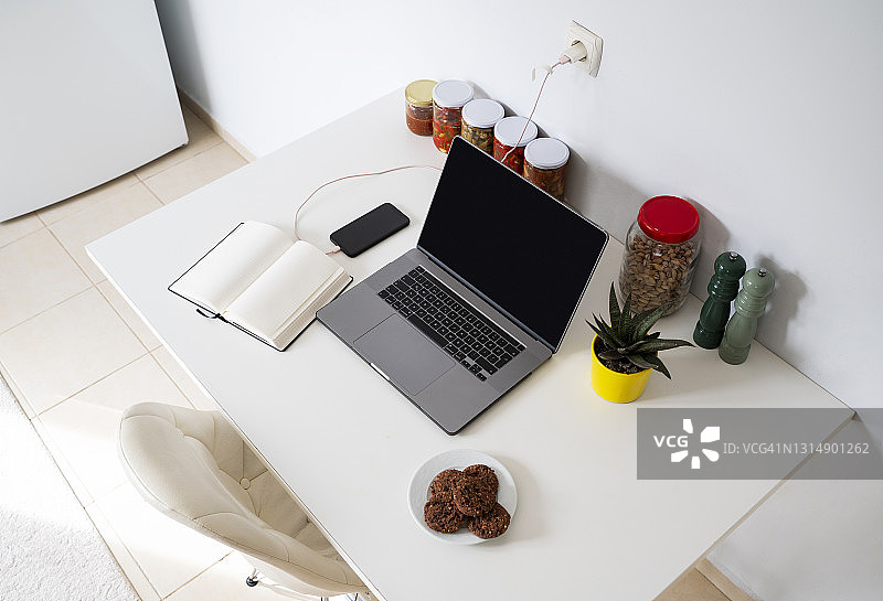厨房桌子上的现代笔记本电脑和笔记本图片素材