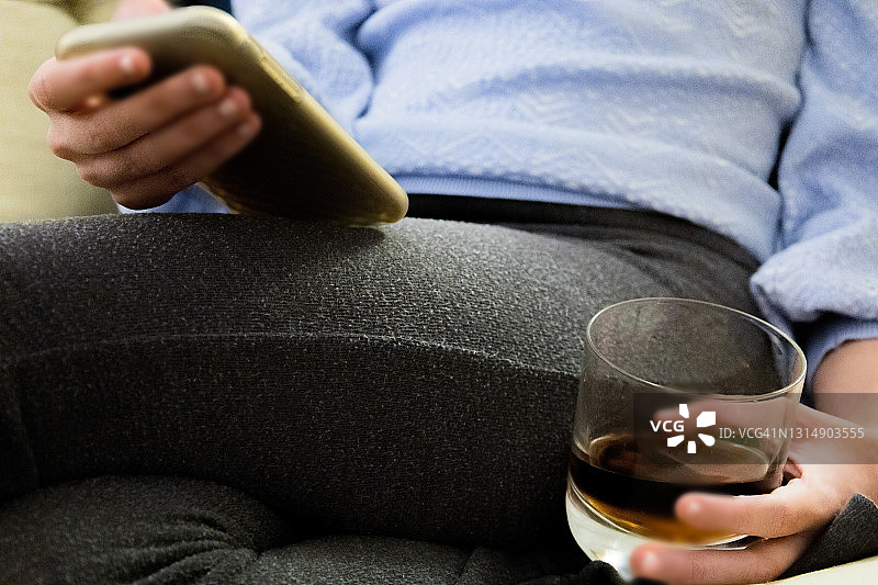 手持智能手机的年轻混血女性拿着睡前威士忌图片素材