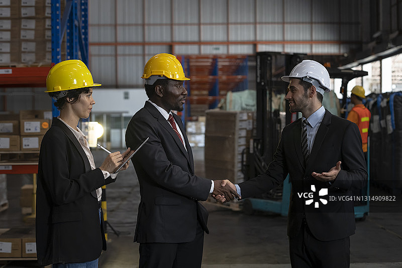 商务人士在仓库握手交谈图片素材