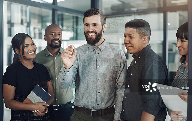 商务人士在办公室的玻璃墙上讨论并记录图片素材