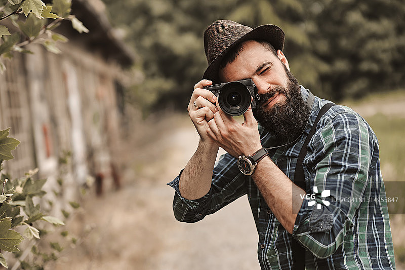 在绿色公园里拍照的络腮胡年轻男人图片素材