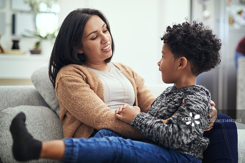年轻母亲坐在沙发上与儿子交谈图片素材