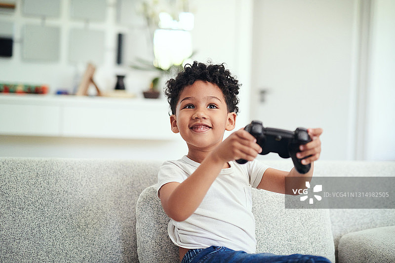 年轻男孩坐在沙发上在家玩游戏场景照片图片素材