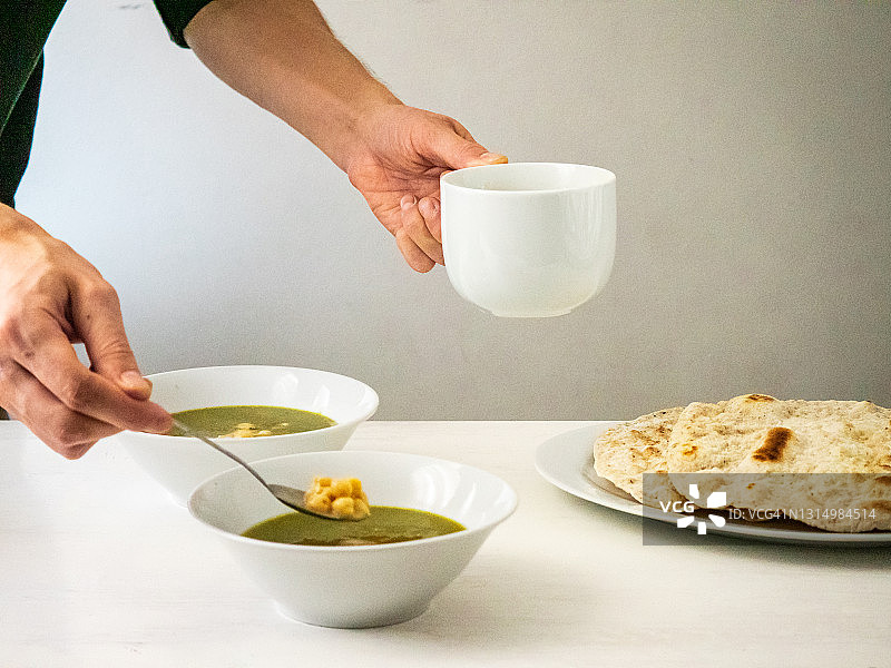 男人用手盛埃及传统秋葵汤，配鹰嘴豆和薄饼图片素材