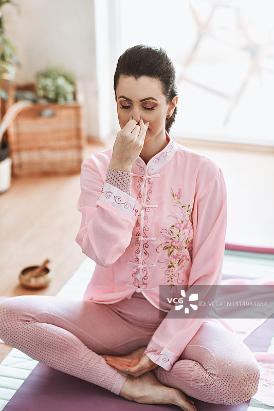 在工作室冥想时练习呼吸的瑜伽女性图片素材