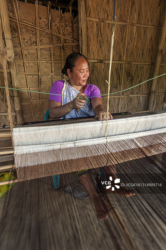 来自印度东北部的女人在传统手摇织布机上编织图片素材
