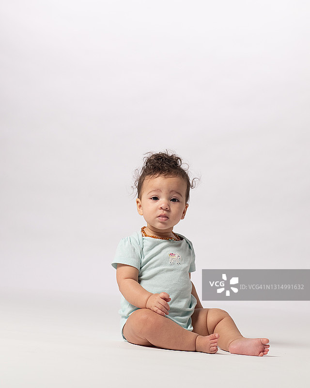 坐在白色背景上的面无表情的女婴肖像图片素材
