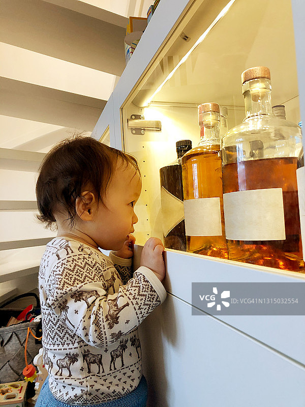 孩子盯着柜子里的酒瓶图片素材