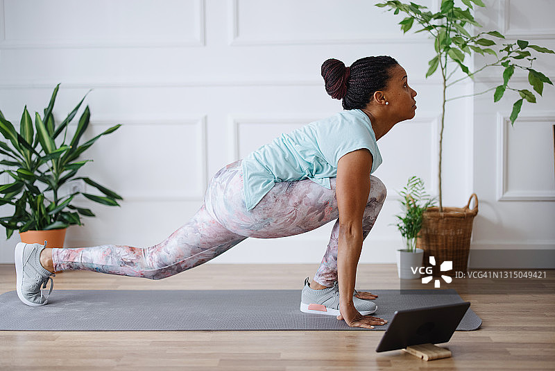 女人在家里使用平板电脑观看练习瑜伽图片素材