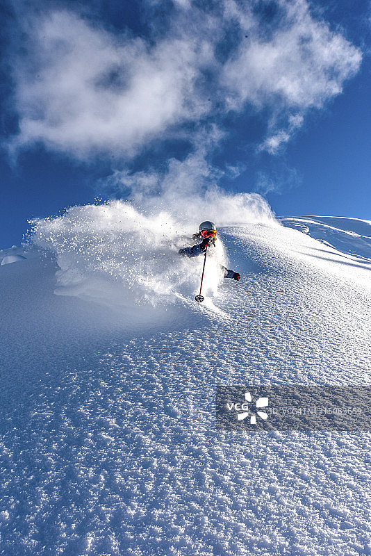滑雪者在新鲜的粉雪中滑下陡峭的山脊图片素材