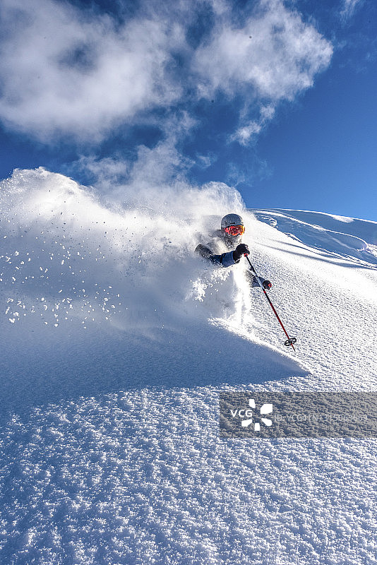 滑雪者在新鲜的粉雪中滑下陡峭的山脊图片素材