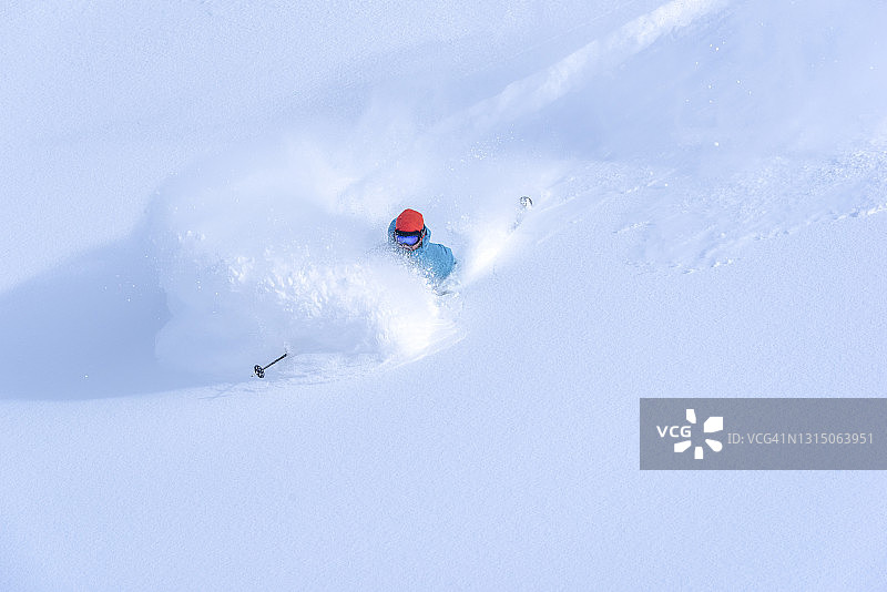 滑雪者在新鲜的粉雪中滑下陡峭的山脊图片素材