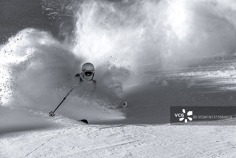 滑雪者在新鲜的粉雪中滑下陡峭的山脊图片素材