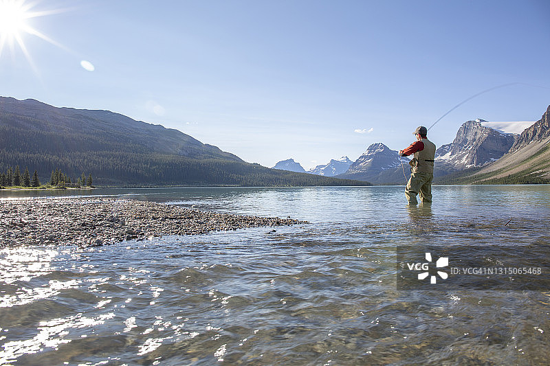 男人在阳光明媚的阿尔卑斯湖上进行飞蝇钓图片素材