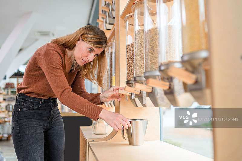 在可持续商店使用谷物分配器的女人图片素材