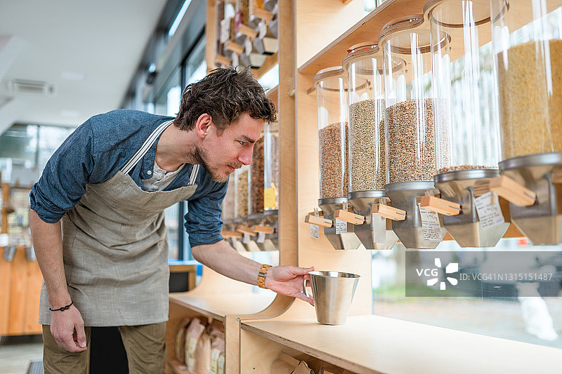 男职员在可持续商店检查麦片分配器图片素材