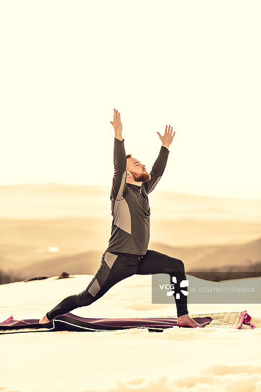 男子在雪山中做低弓步瑜伽图片素材