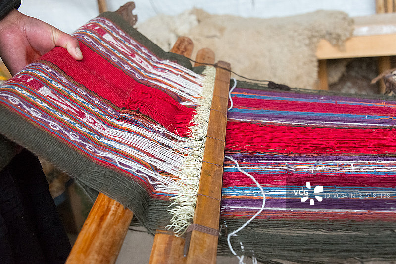 秘鲁圣谷钦切罗当地妇女用旧织布机制作的彩色织物特写，羊驼毛织物图片素材