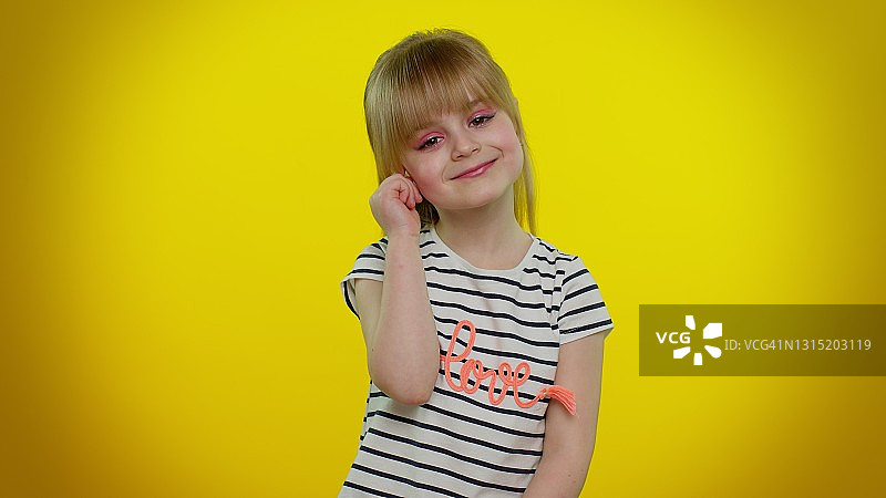 在黄色背景中摆姿势的微笑美丽金发小女孩图片素材