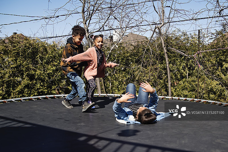 兄妹在春天户外蹦床上跳跃图片素材