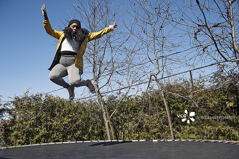 春天户外在蹦床上跳跃的快乐女人图片素材