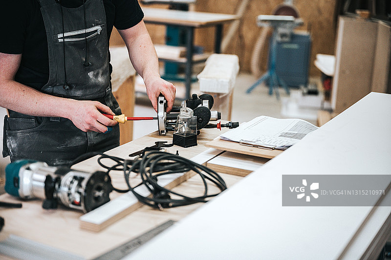 工人在工作台上用螺丝刀调整路由器图片素材