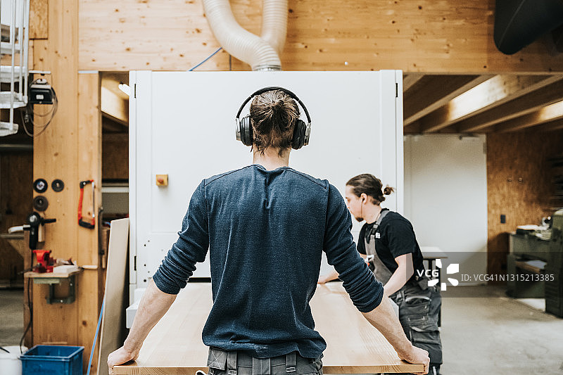 年轻木匠用带式研磨机拉动木板图片素材