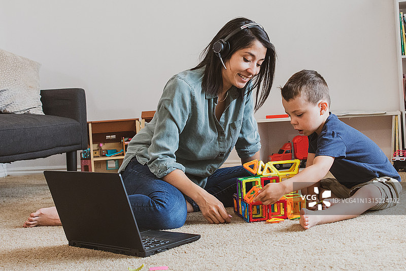 年轻母亲工作通话孩子在一旁玩耍图片素材