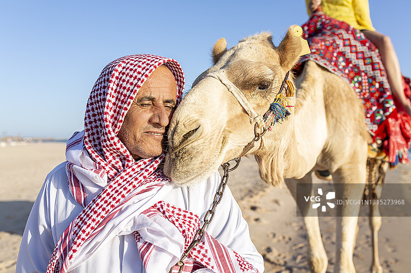 骆驼和骆驼司机在海滩旁的肖像图片素材
