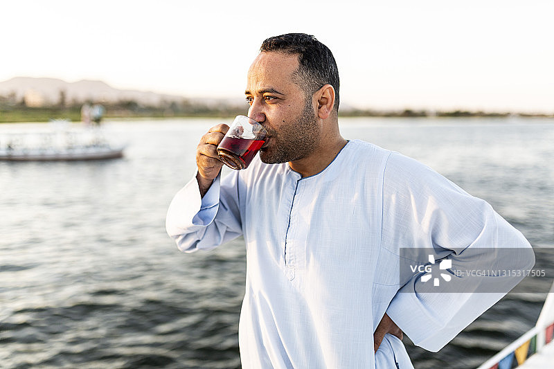 穿着传统服装的埃及男人在日落时享受茶的真实肖像图片素材
