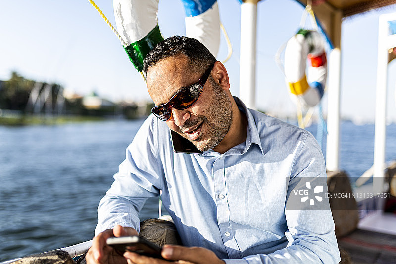 来自埃及的商人正在船上使用手机图片素材