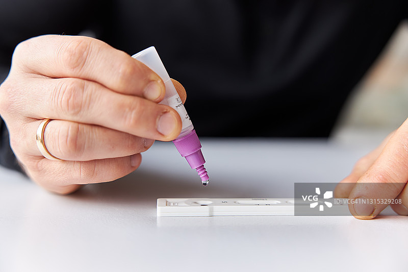男子在白色桌子上做新冠快速抗原检测特写图片素材