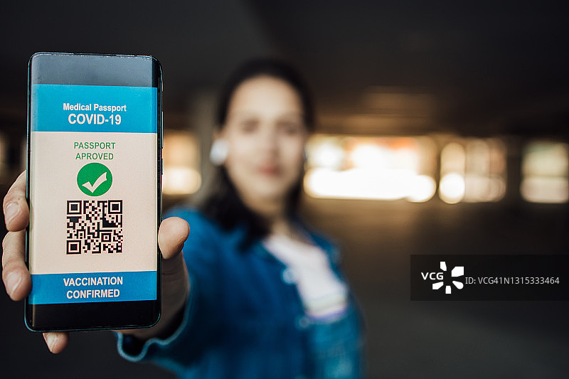 年轻女子在智能手机上展示电子疫苗证书图片素材