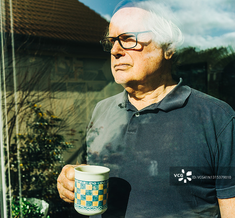 一位中年男人从窗户望向后花园图片素材