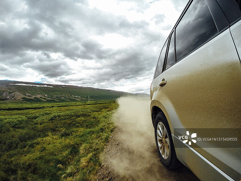 SUV在开阔的乡村景观中沿土路高速行驶图片素材