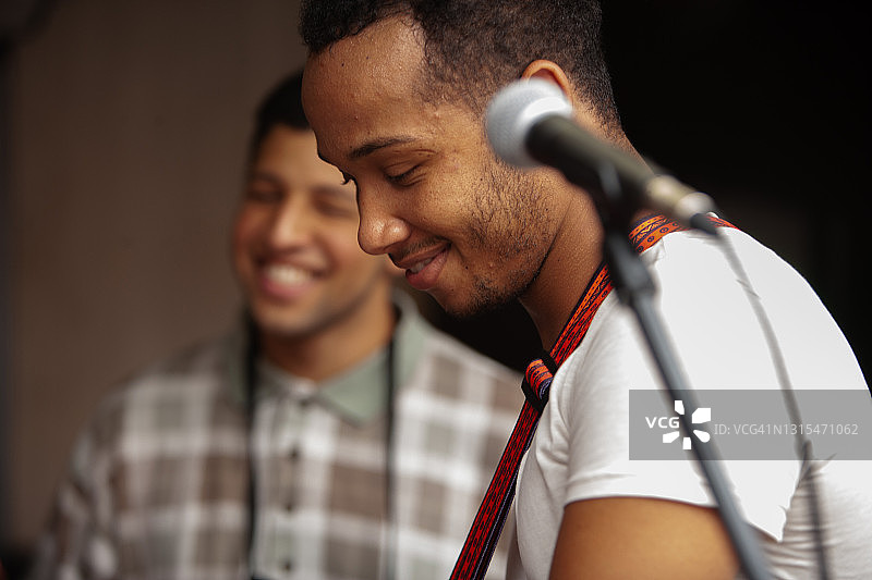 年轻的音乐家自然地笑着弹吉他图片素材