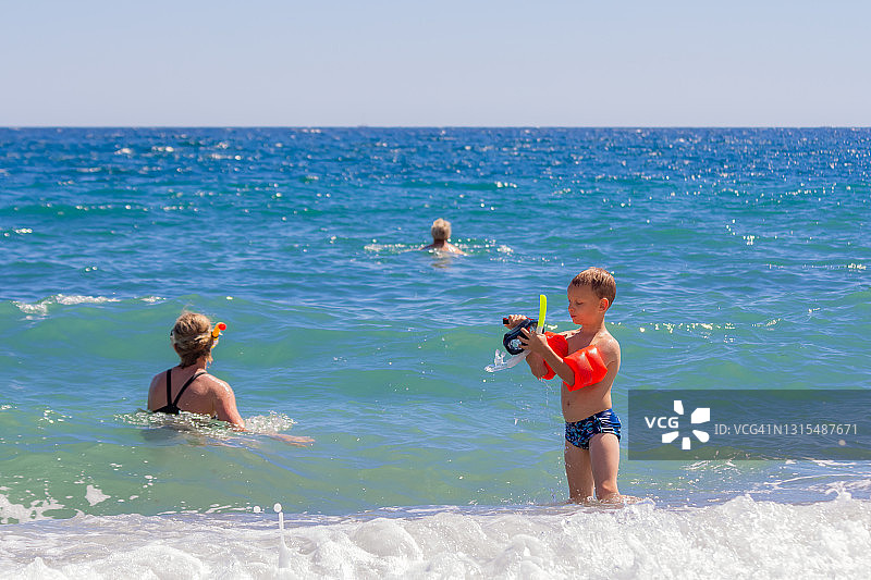 一家人和两个孩子在海滩夏季假期玩耍，戴着浮潜面罩和游泳圈在海里游泳图片素材