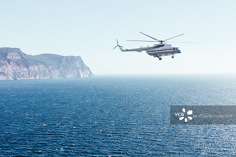 救援搜索直升机飞越海面。在多风天气和强烈的海浪中监视海岸。蓝色天空中的飞行器图片素材
