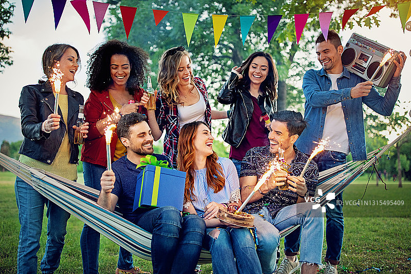 快乐的朋友们在公园里庆祝生日，玩得很开心图片素材