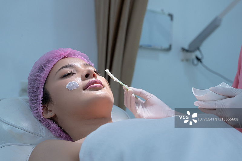 美容师在美容诊所为亚洲年轻女性的面部进行磨砂护理，化妆品外科手术，面部化学焕肤疗法图片素材