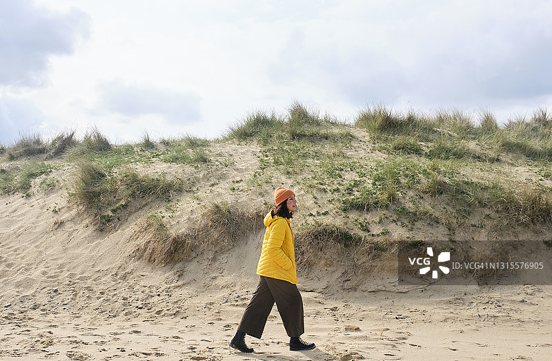 女子在有沙丘的海滩上散步度假图片素材