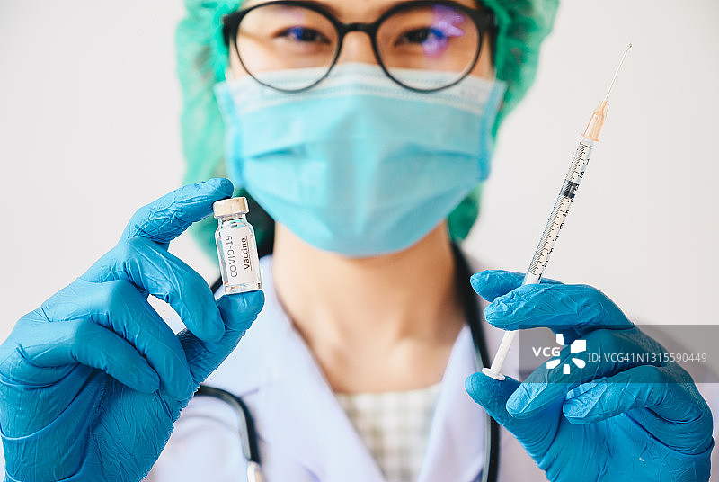 女医生手持装有新冠疫苗的注射器，准备为病人注射图片素材