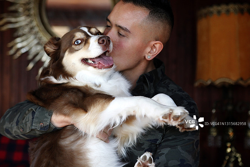 男人抱着狗亲吻脸颊侧面图片素材