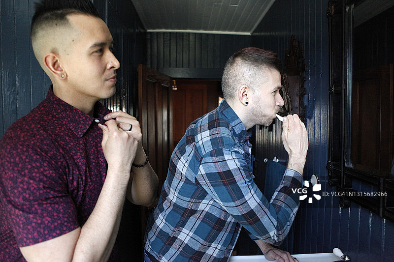 中年男士在浴室照镜子，其中一人正在刷牙图片素材