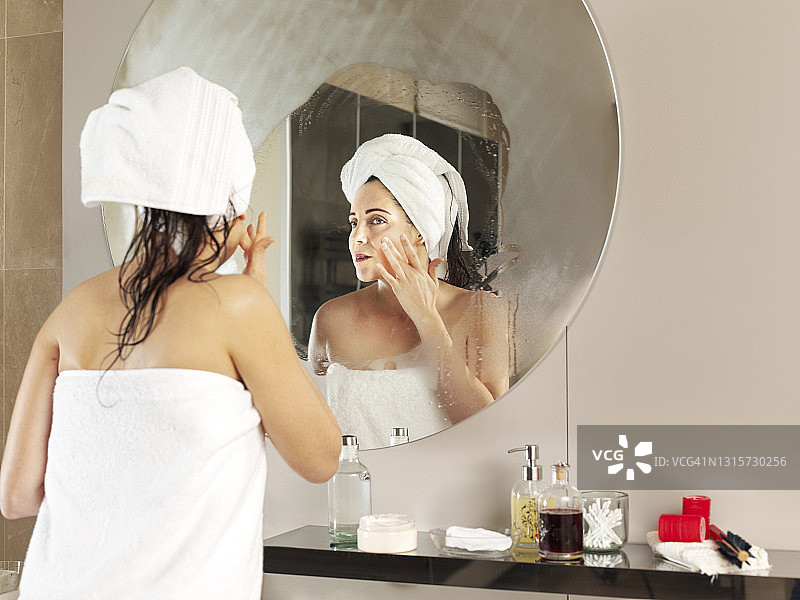 美女沐浴后在脸上涂抹保湿霜图片素材